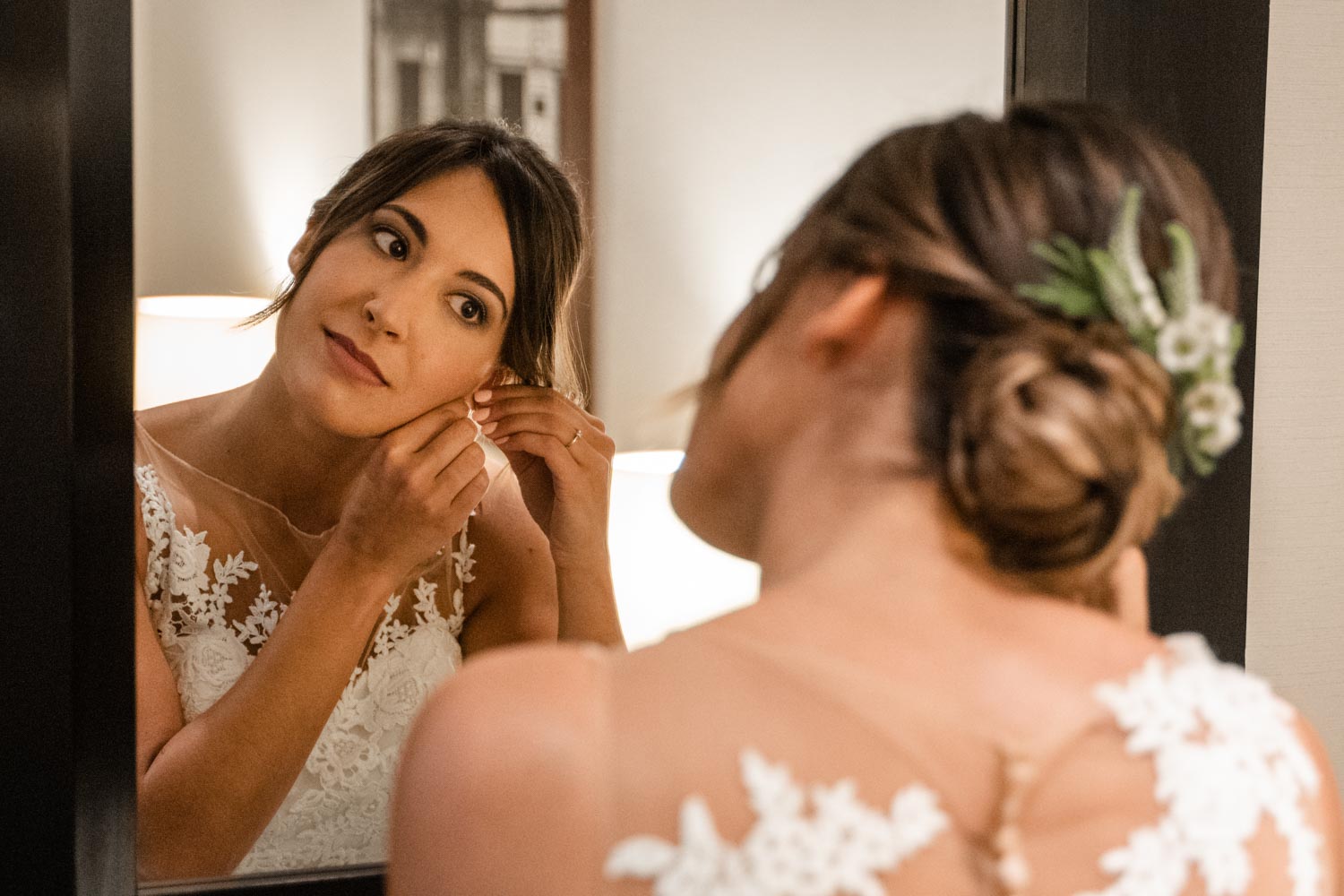 la novia colocándose los pendientes frente al espejo